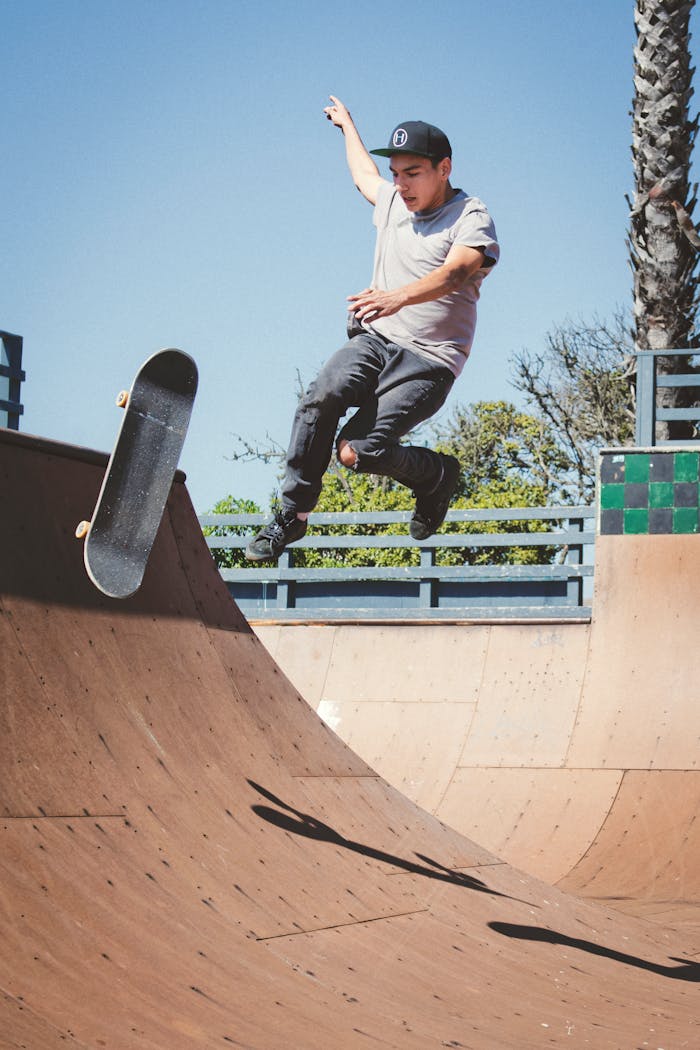 A skateboarder executes a trick on a wooden ramp in a sunny California skatepark.